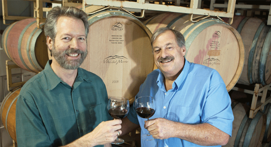 Villa del Monte Winery owners in front of wine barrels