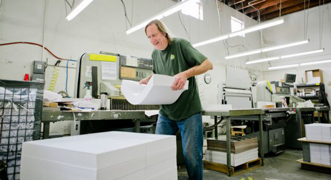Clint Bower moves a heavy stack of papers during a busy day of work at the cooperatively owned Community Printers.