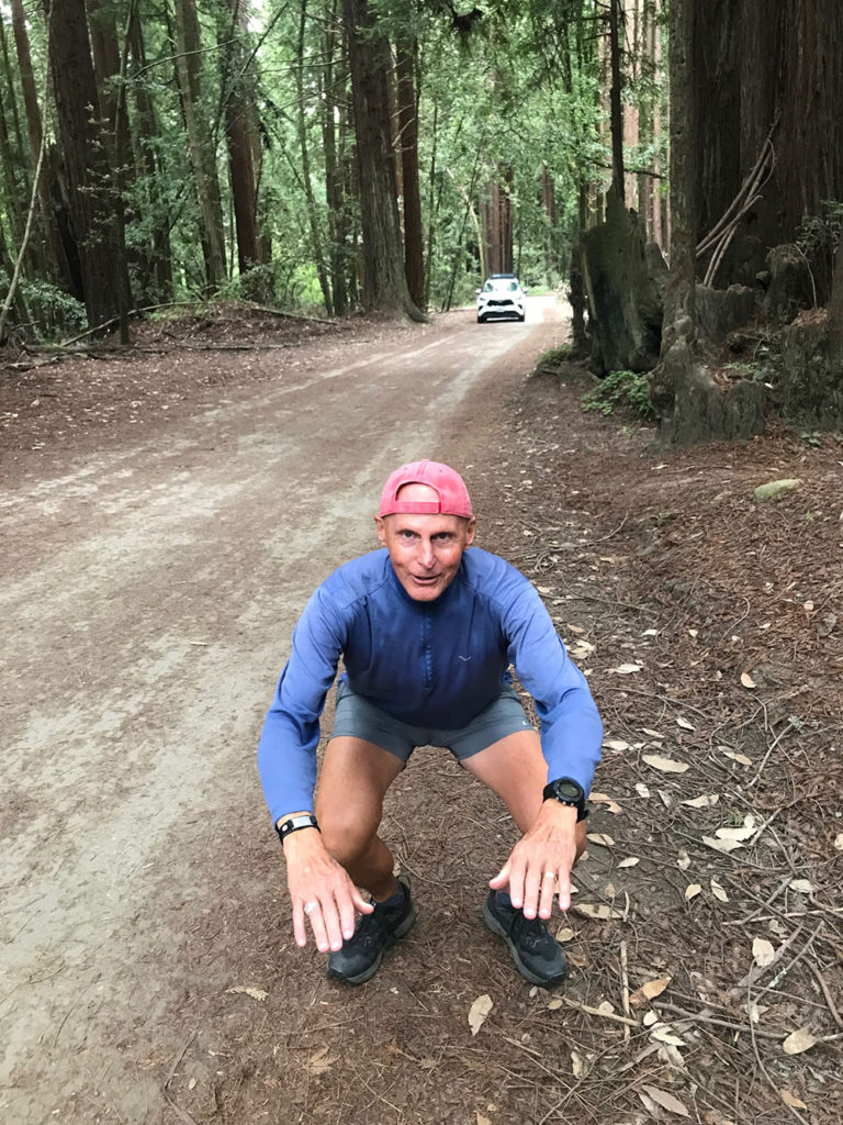 Guy doing squats on a forest trail