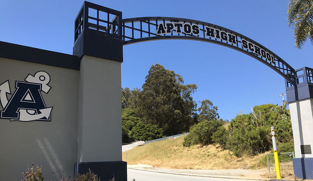 Arch over the entrance of a driveway with a sign for Aptos High School