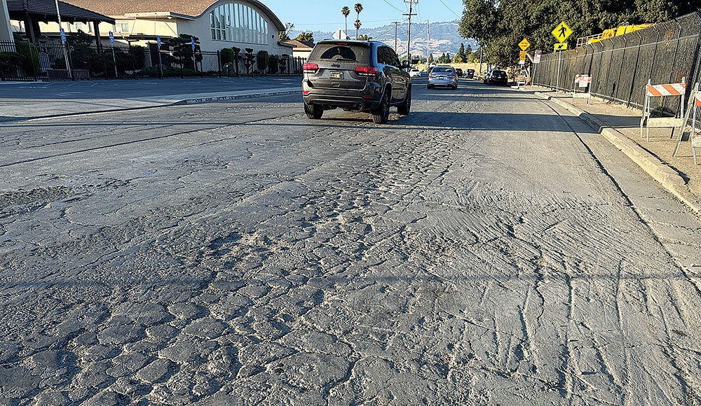 car driving down a road with lots of cracks and potholes