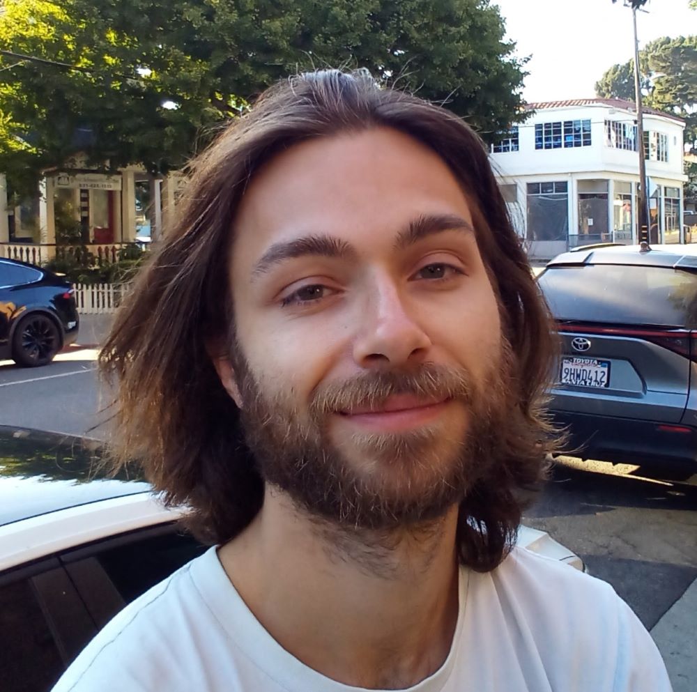 27 year old Fraser Nash with long brown hair, beard and white t-shirt