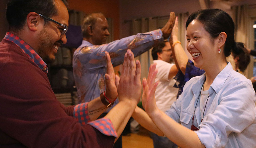 People in a group raising their hands to touch others