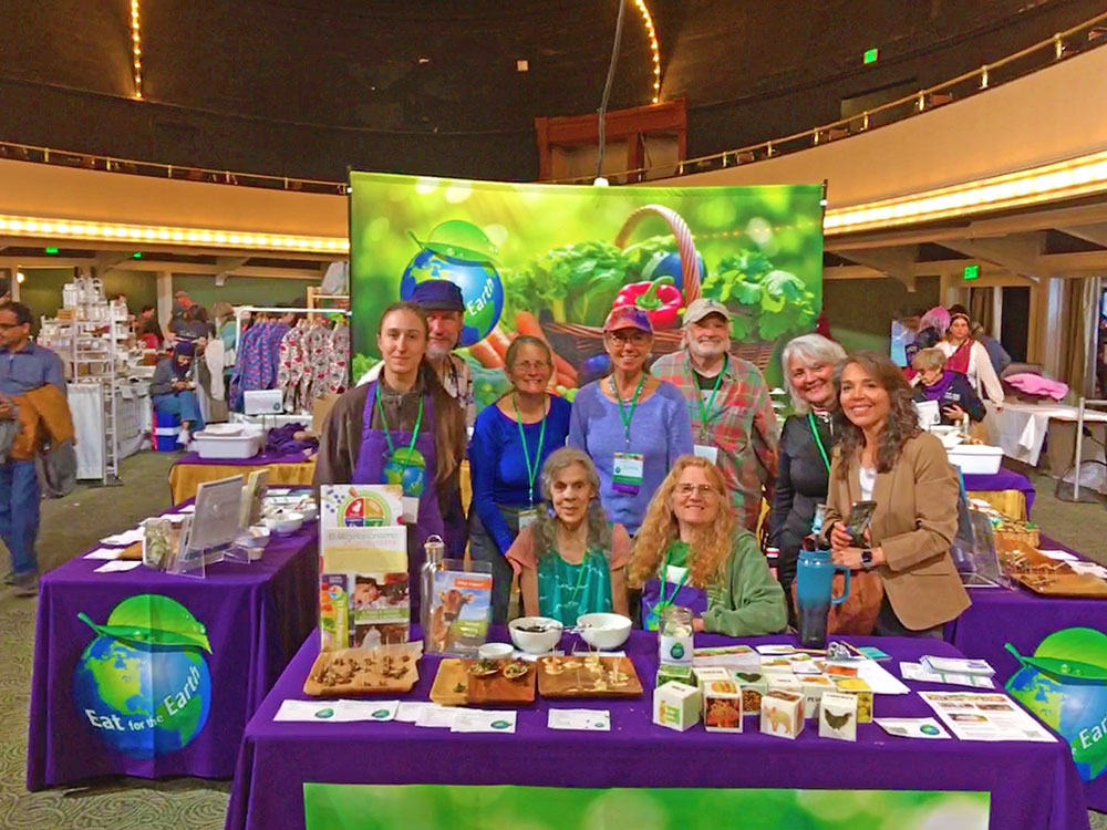 Group of eight people at an Eat for the Earth booth inside a building