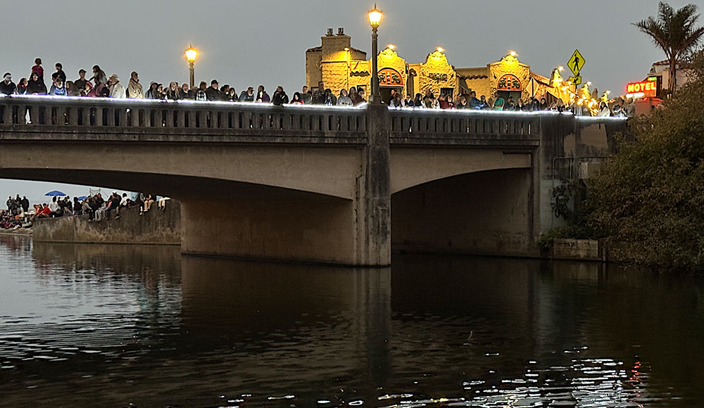 Bridge over a river at dusk with people lined up along its length