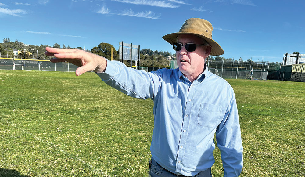 Man in a hat on a soccer field pointing