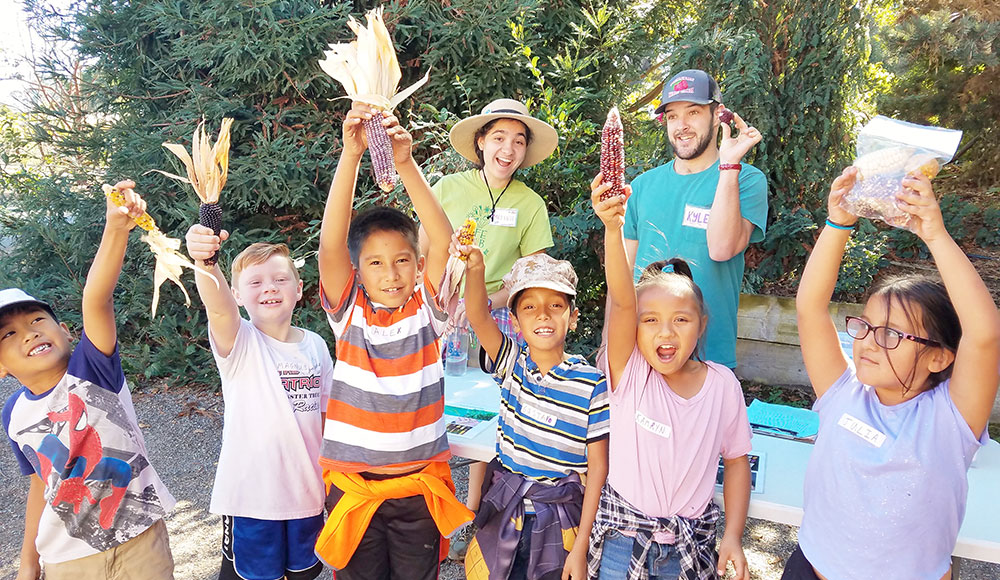 Kids outdoors holding up dried Indian corn