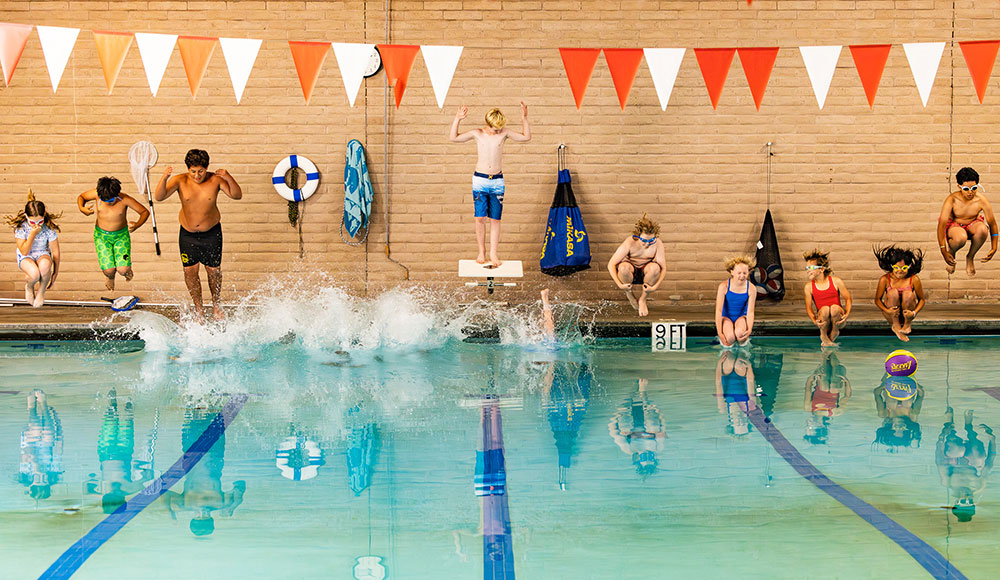 A row of kids jumping into a swimming pool