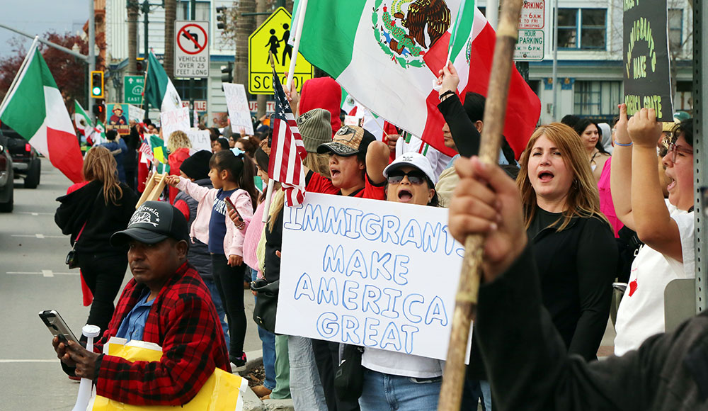 Group of people holding up signs and Mexican flags on the street