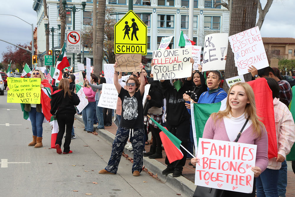 People lining a street, holding up signs in support of immigration